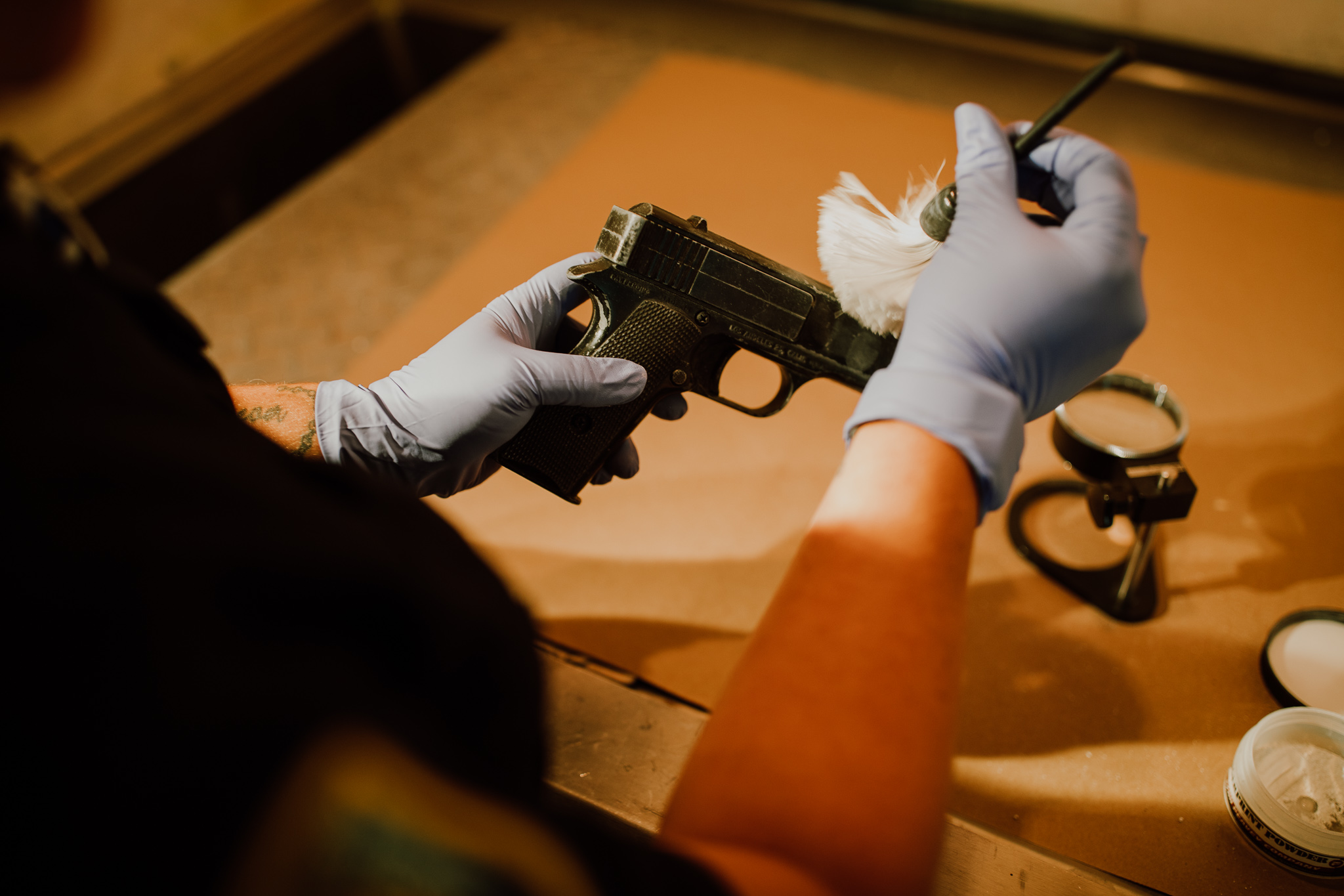 Photo of a detective checking a gun for fingerprints.