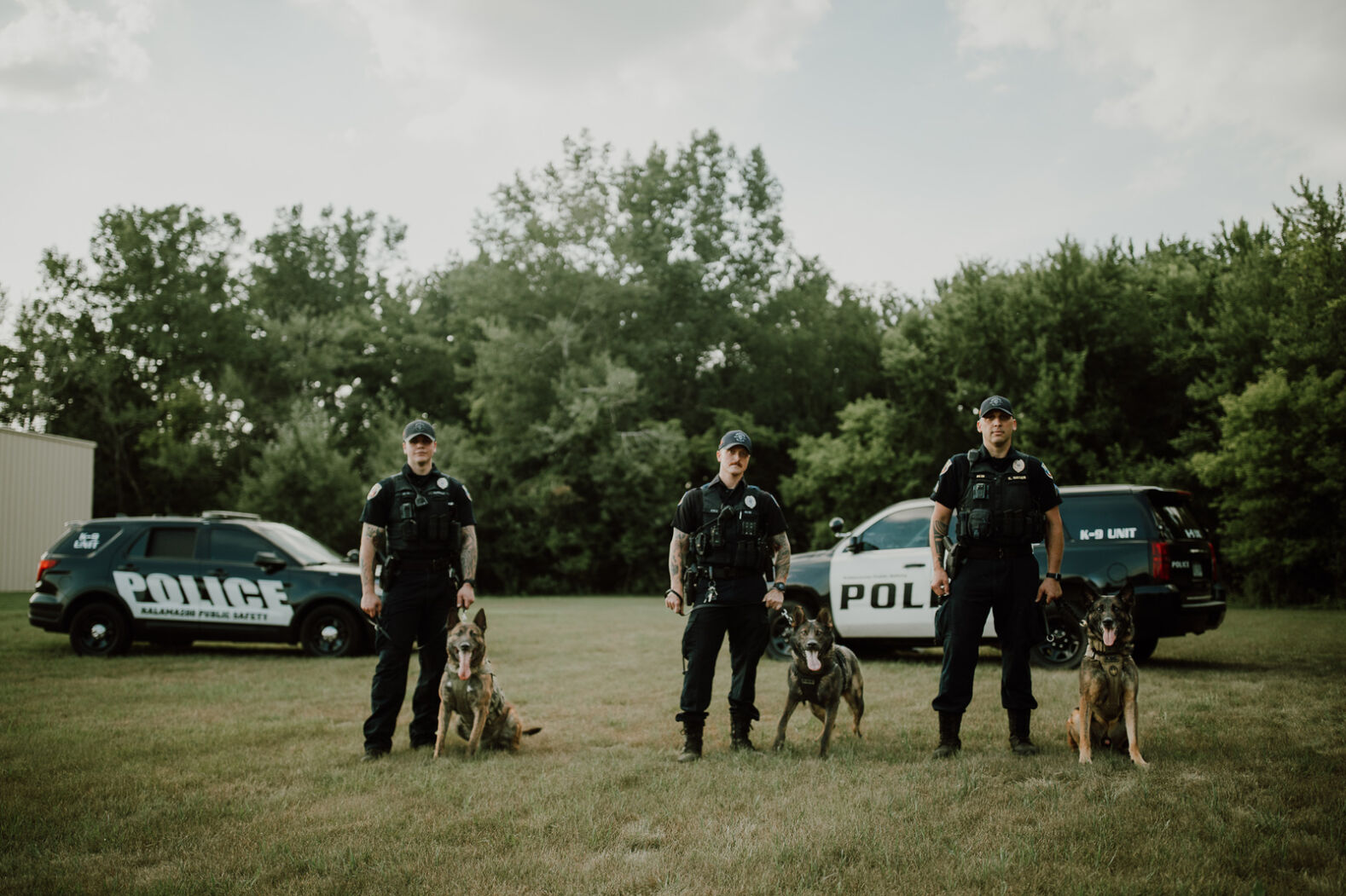 Three Public Safety Officers pose with police canines
