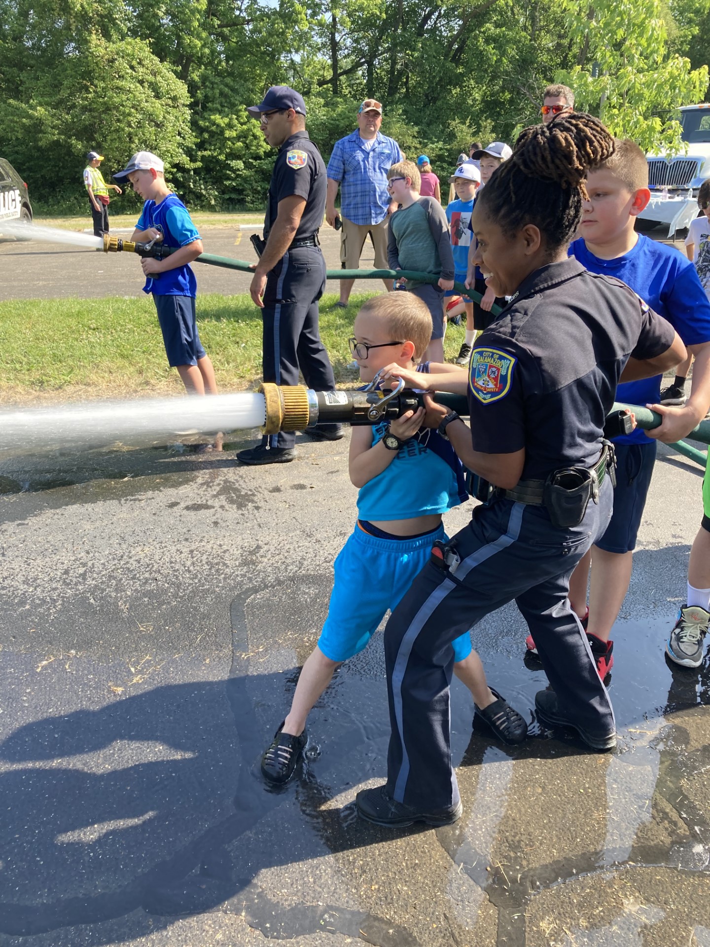 Photo of an officer and a child using a fire hose.